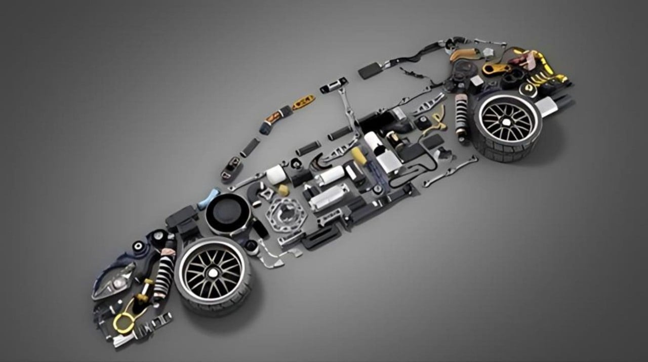 An arrangement of various car parts, including wheels, suspension, engine, and transmission, laid out in the shape of a car on a grey background.
