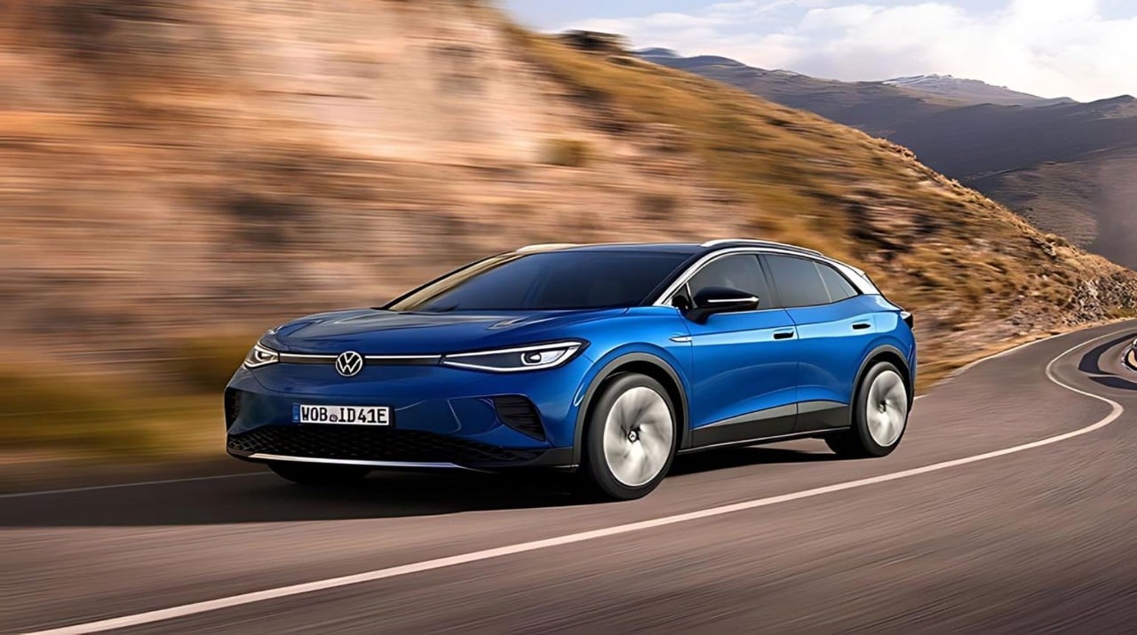 A blue Volkswagen EV driving on a winding mountain road with blurred background.